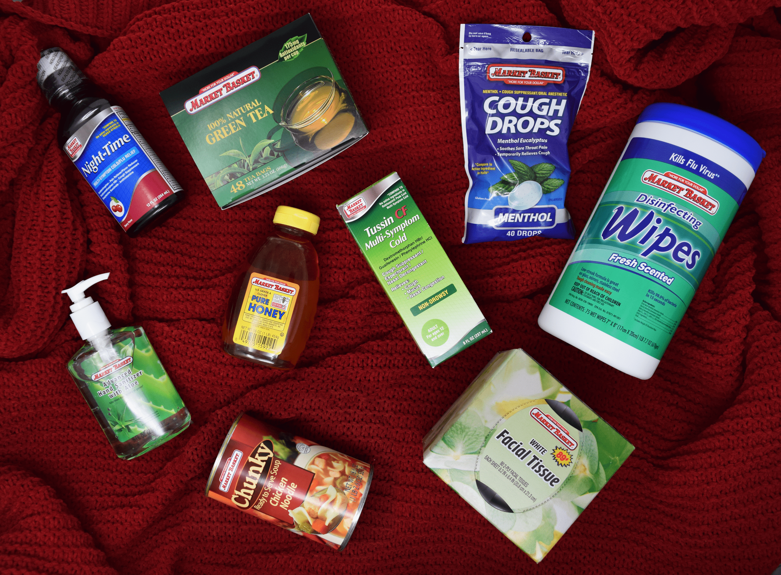 Market Basket brand cold and flu products and sick day essentials laid out on a red blanket