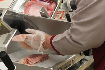 A Market Basket associate slicing deli meat