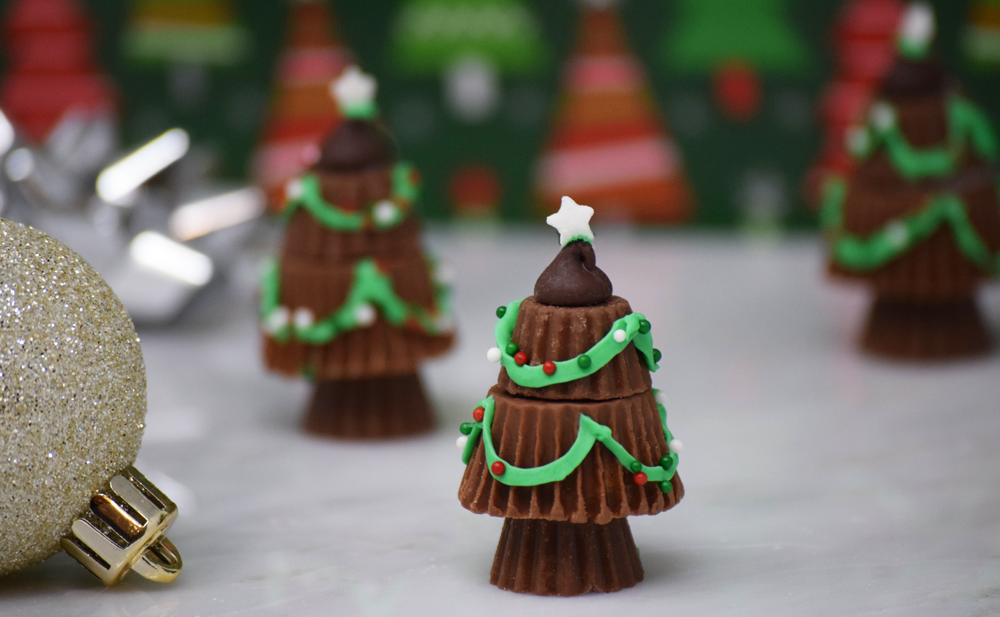 Peanut butter cup Christmas trees on a marble table with ornament decorations