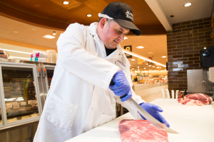 Meat department associate cutting meat